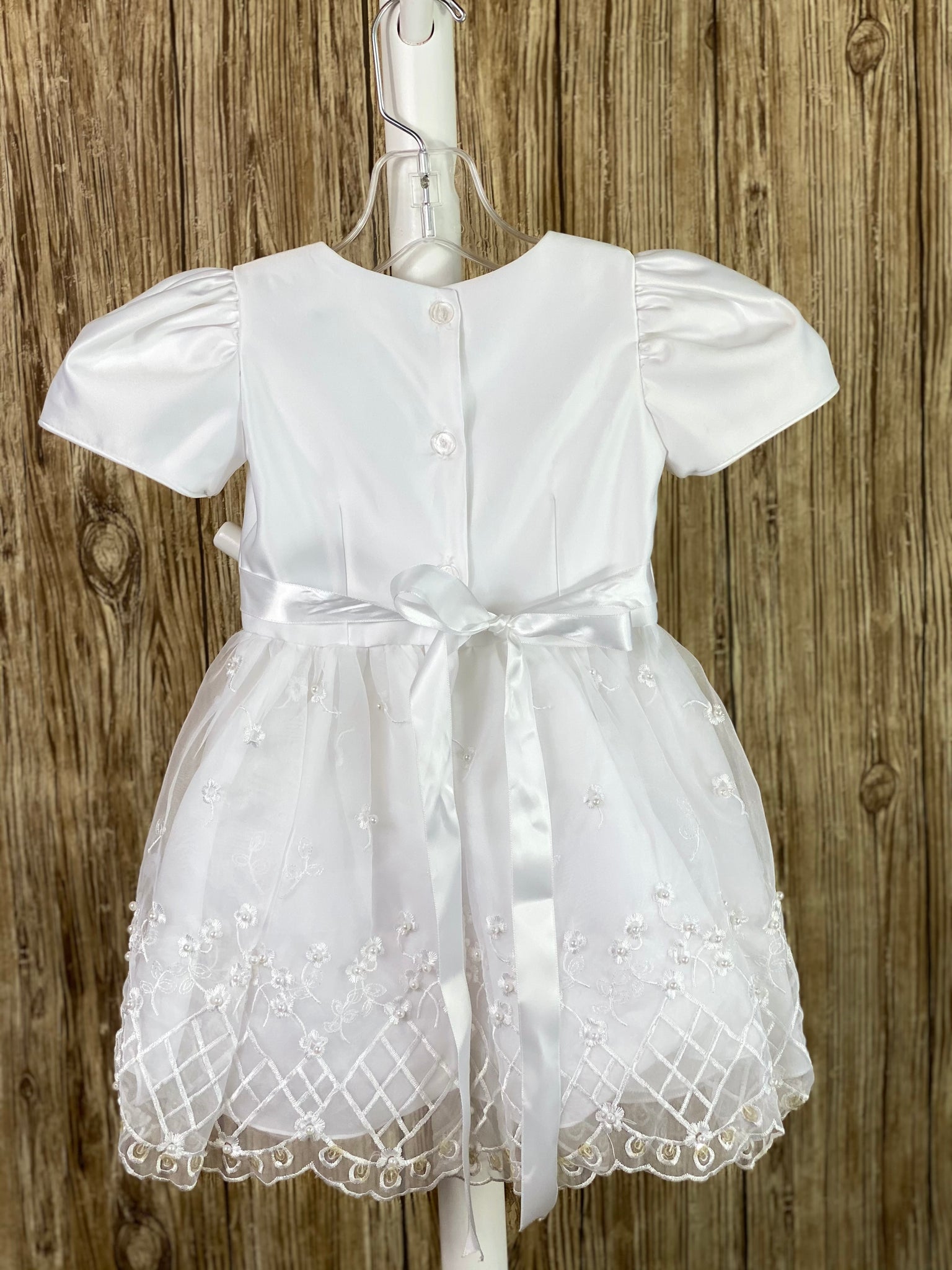 This a beautiful, one-of-a-kind baptism gown.  A lovely gown for a precious child.  White, size 12M Simple satin bodice Satin gathered sleeves Bow in center of bodice Satin skirt with harlequin floral lace Ribbon bow in back Lace vest  Feathered trim on vest Bows on right and left side of vest