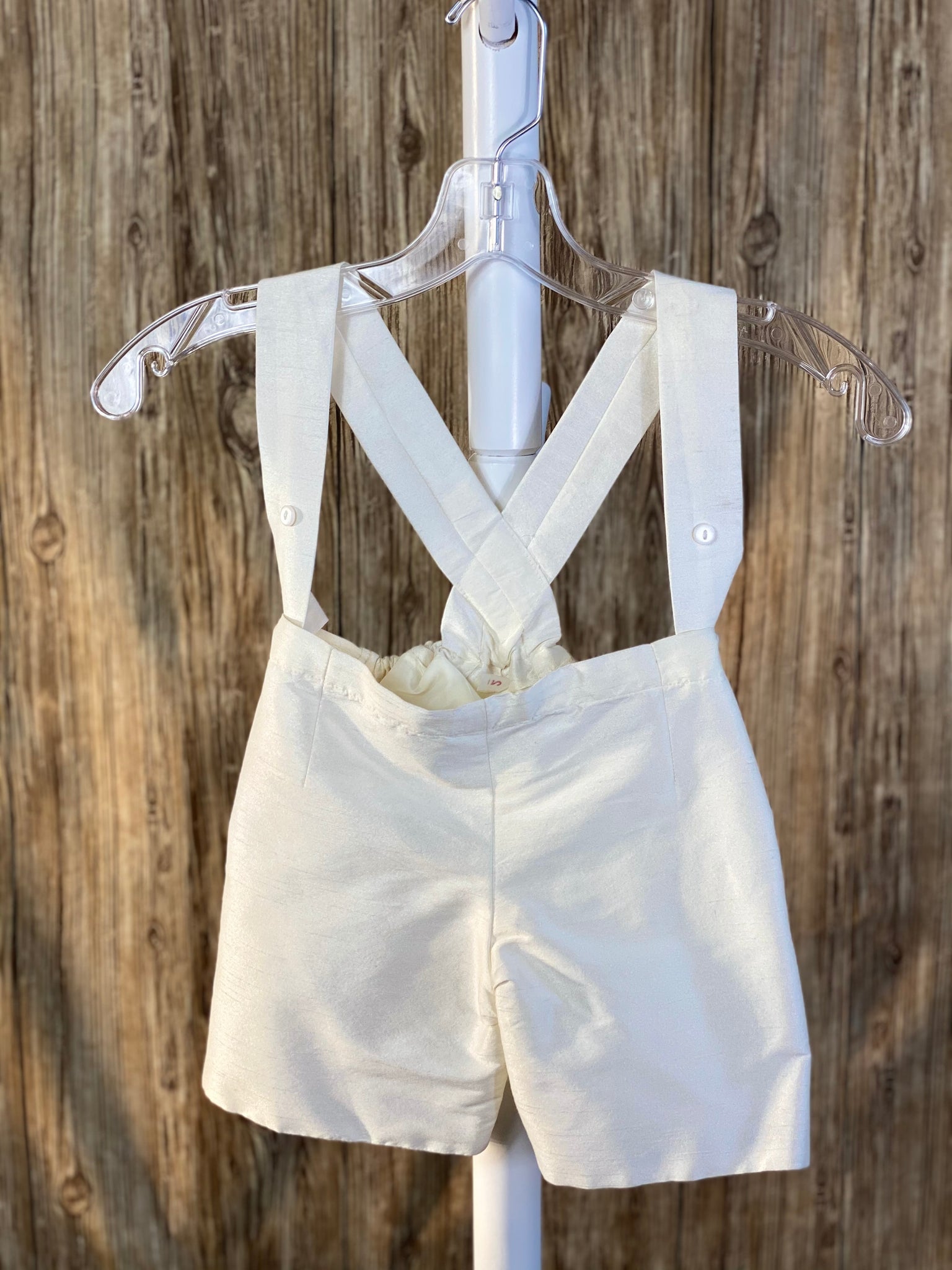 This a beautiful, one-of-a-kind boy’s baptism gown/set.  Lovely clothes for a precious child.  Ivory, size 24M 2- piece set including shirt and suspender pants Collared shirt with short sleeves Simple satin pants Twisted layered trim along shirt cuffs Twisted layered trim on shirt bodice Hidden button closure in front Elastic on the back of pants