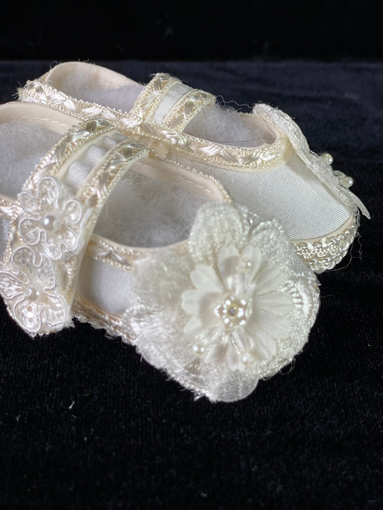 Elegant handmade ivory baby girl shoes with embroidery, lace, flowers, and pearls.