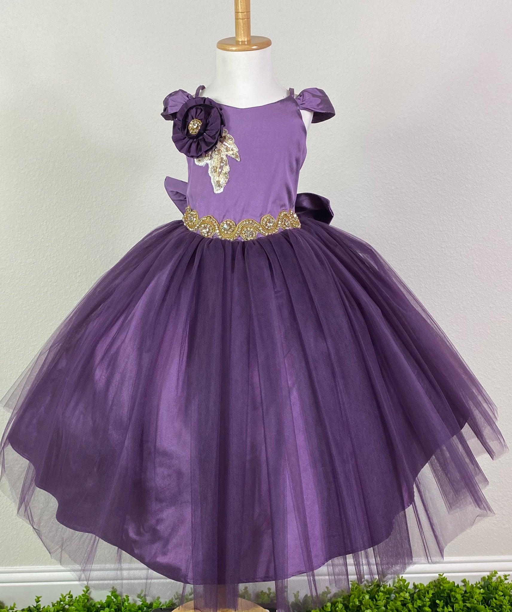 Satin bodice with off the shoulder cap sleeves Large flower on right shoulder Gold swirl rhinestone belting Satin skirting with tulle overlay Corset style backing Large satin bow on back Dress pictured with a petticoat Petticoat not included  Choose from a tulle, cloth, or wire for best look