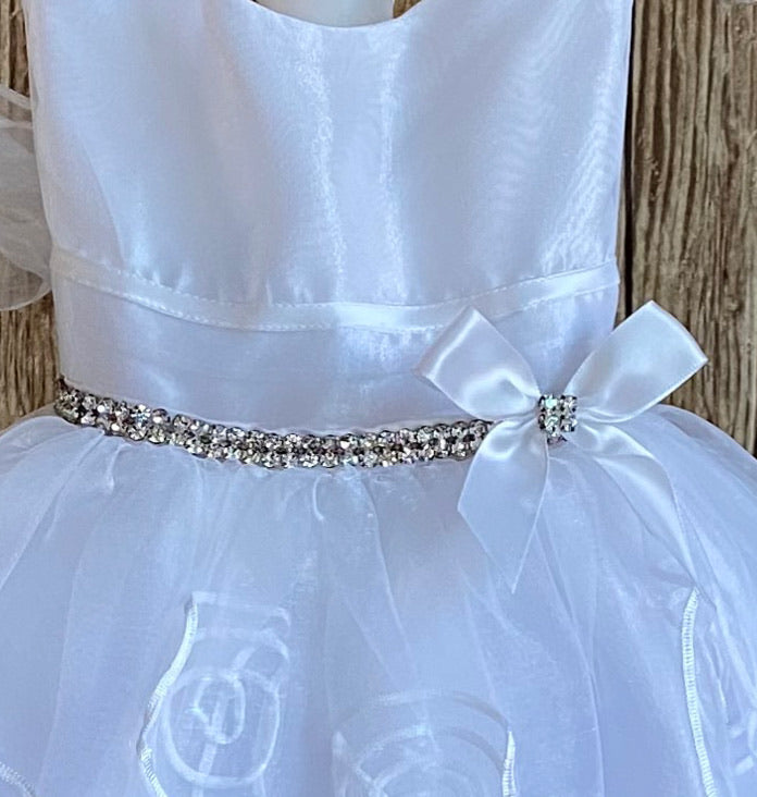 This a beautiful, one-of-a-kind baptism gown.  A lovely gown for a precious child.  White, size 12M Satin bodice with no sleeves  Chiffon ribbon going along bodice Rhinestone belt going along edge of bodice with satin bow Tulle skirting with embroidered swirls