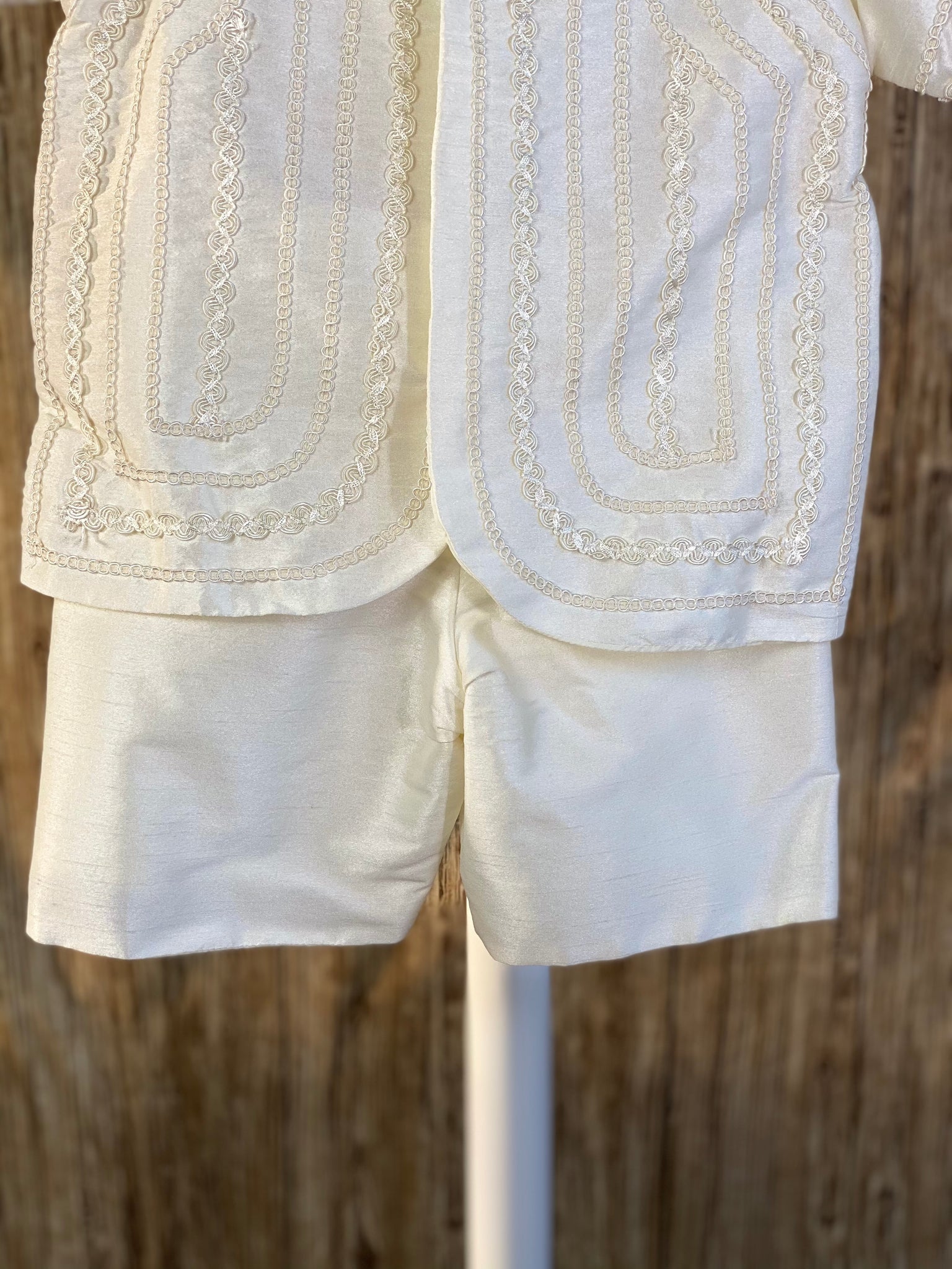 This a beautiful, one-of-a-kind boy’s baptism gown/set.  Lovely clothes for a precious child.  Ivory, size 24M 2- piece set including shirt and suspender pants Collared shirt with short sleeves Simple satin pants Twisted layered trim along shirt cuffs Twisted layered trim on shirt bodice Hidden button closure in front Elastic on the back of pants