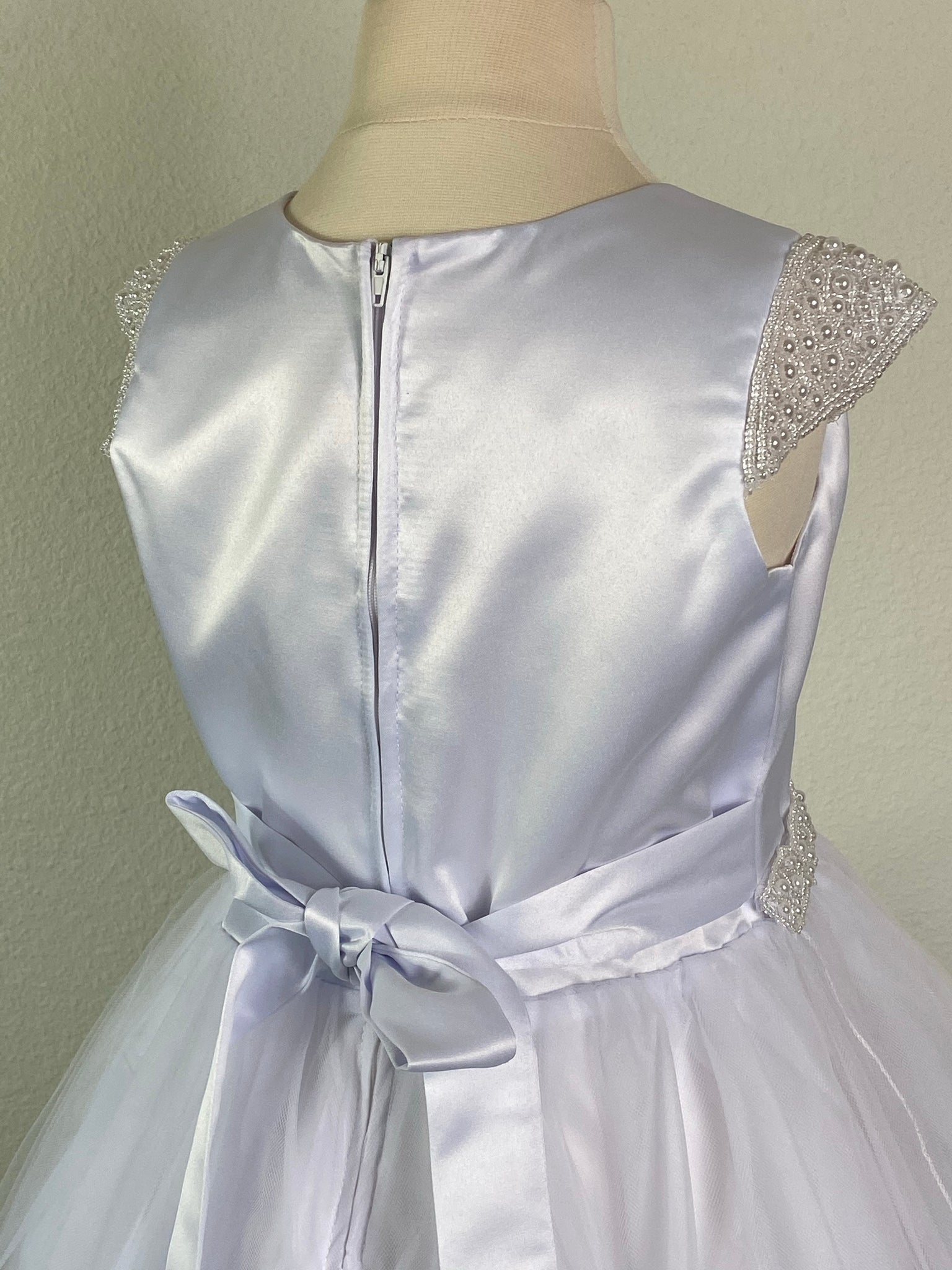 White, size 10 Pearl cap sleeve Satin paneled bodice Thin beaded belt Satin skirt with tulle overlay Zipper closure Satin ribbon for bow