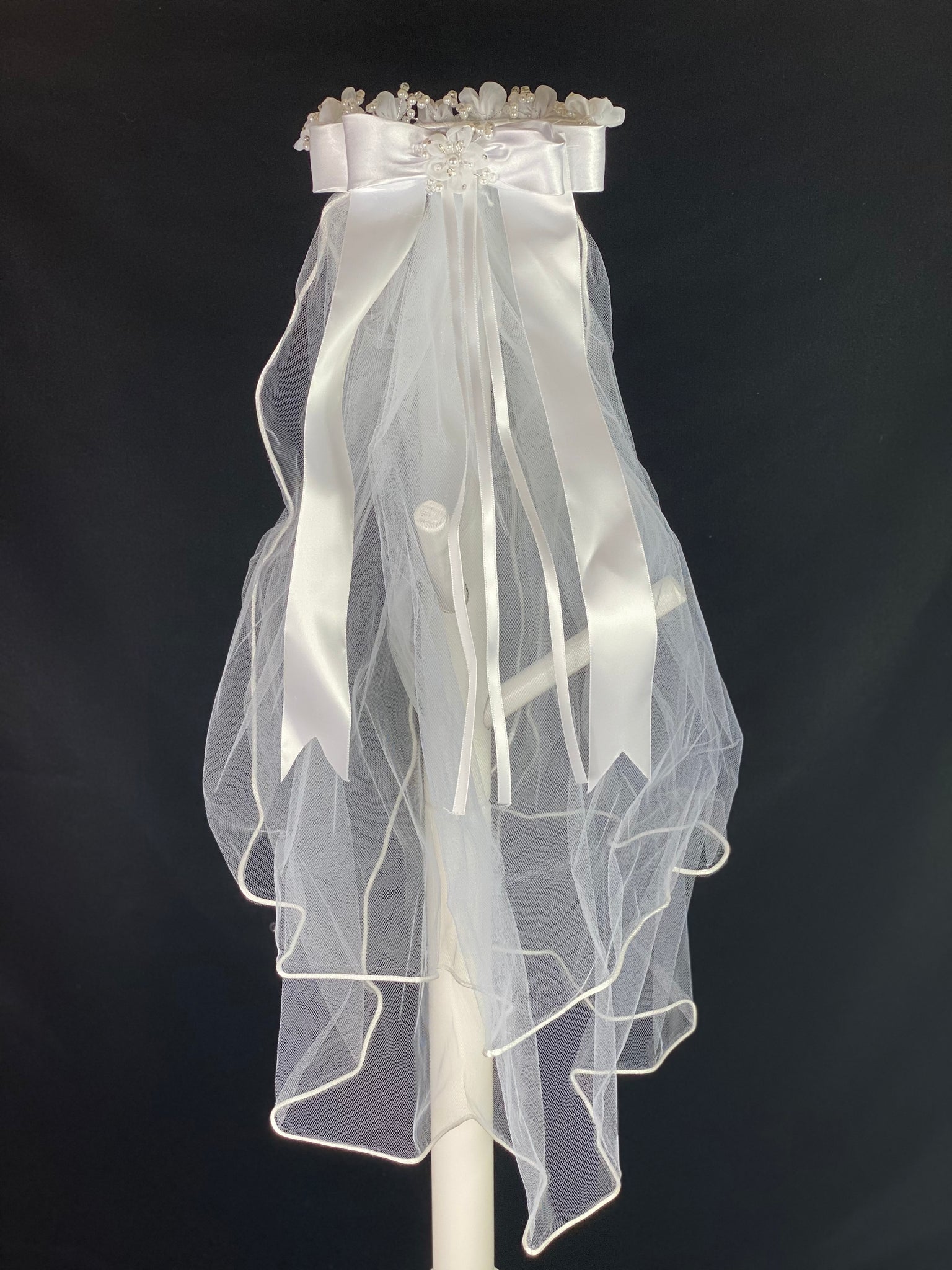 Elegant soft 2 layer tulle veil with delicate hand stitched braided satin trim around the edge and  Handmade flower halo crown with veil with large white satin bow on back. Organza flowers with sparkling rhinestone petals and pearl centers. Beautiful pearl leaves sticking out around flowers. This double layered veil reaches approximately 24" long, with a crown diameter of 6". Veil has 2" long, 3" wide, comb to secure it in place. 