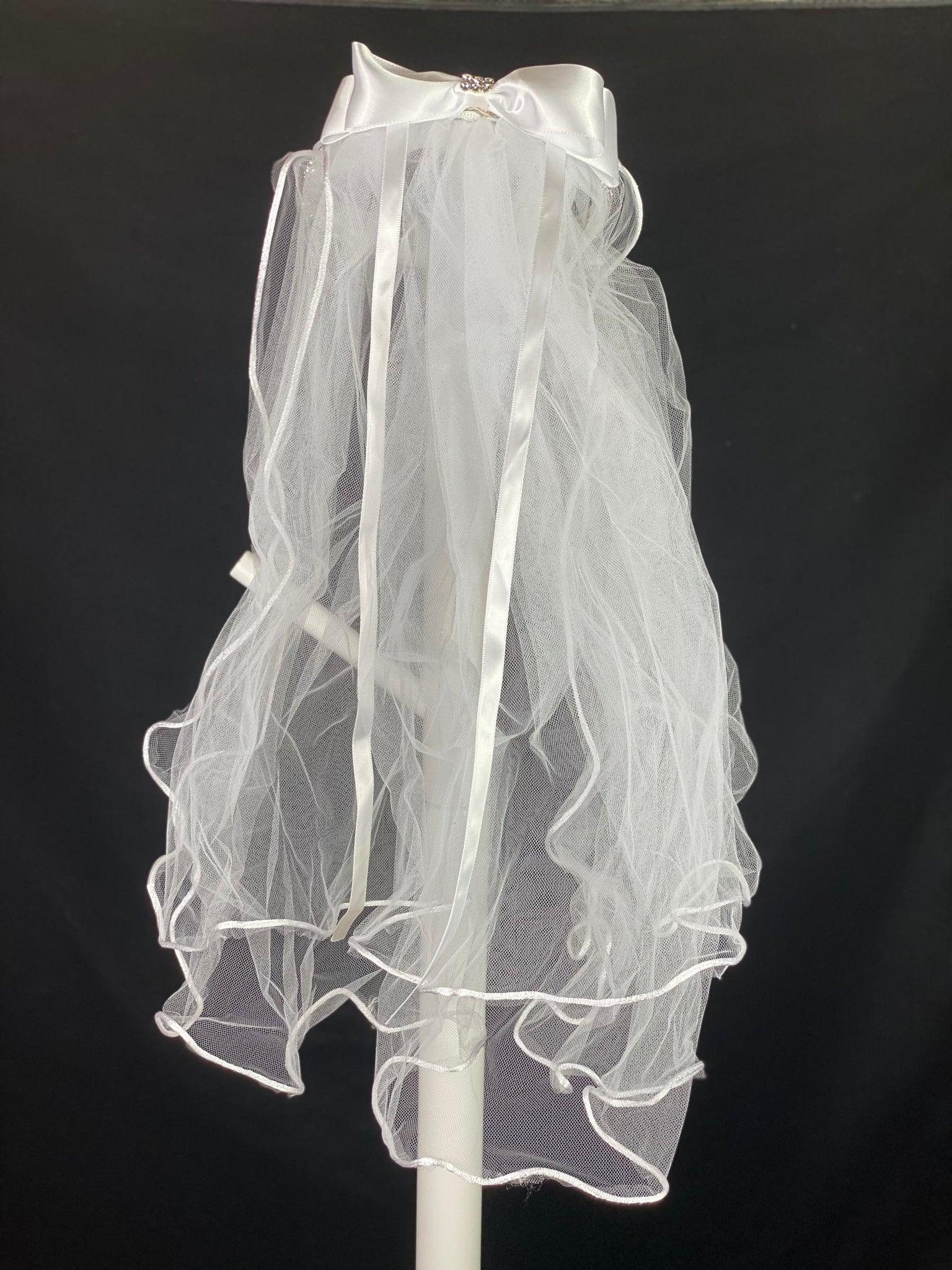 Elegant soft 2 layer tulle veil with delicate hand stitched braided satin trim around the edge and handmade flower halo crown with veil with large white satin bow on back. Beautiful sparkling rhinestone band around crown. Ivory pearl center on sparkling rhinestone bow.  This double layered veil reaches approximately 24" long, with a crown diameter of 6". Veil has 2" long, 3" wide, comb to secure it in place. 