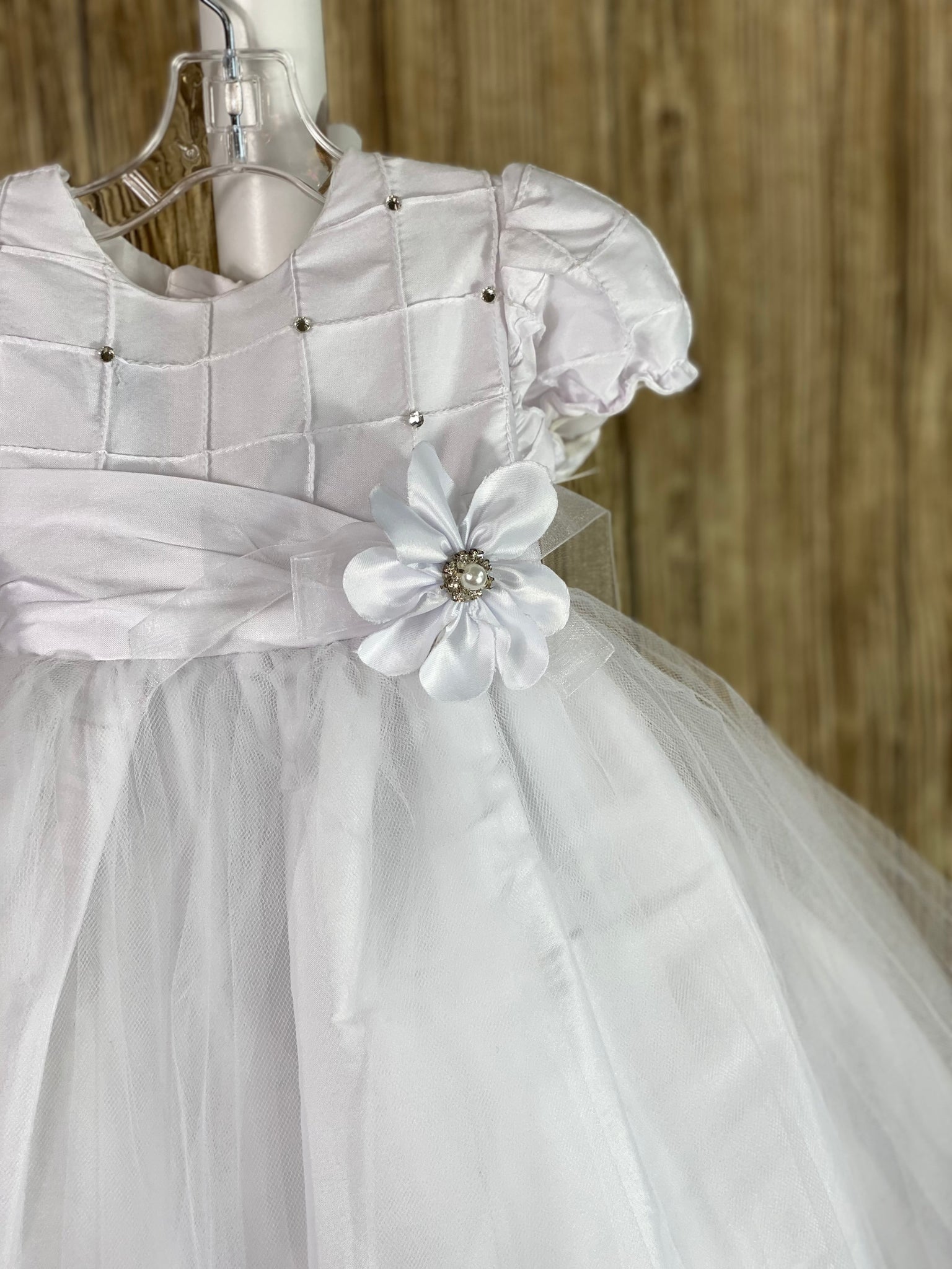 This a beautiful, one-of-a-kind baptism gown.  A lovely gown for a precious child.  White, size 12M Cubed satin bodice with rhinestones Satin cubed sleeves Satin belt with flower Tulle skirting with satin underlay Satin bow in back Button closure