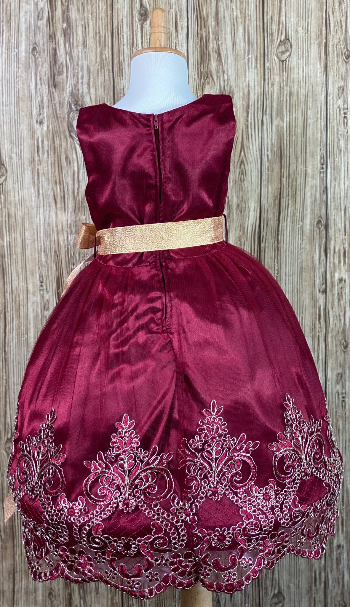 Burgundy satin bodice with tulle overlay Gold ribbon for bow in front or back Embroidered gold applique along edge of skirting Zipper closure Dress pictured with a petticoat Petticoat not included  Choose from a tulle, cloth, or wire for best look