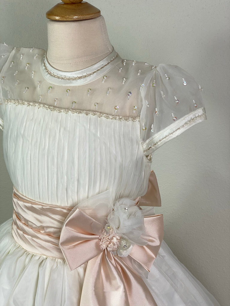 Ivory, size 10 Hand-stitched edging along sleeves and neckline Mesh and satin illusion bodice with beaded detailing and pleats Peach ruched cummerbund Large satin bow on front with floral detailing in center Meshed skirt with braided stripes along bottom Satin covered button closure Peach ribboning for large bow in back