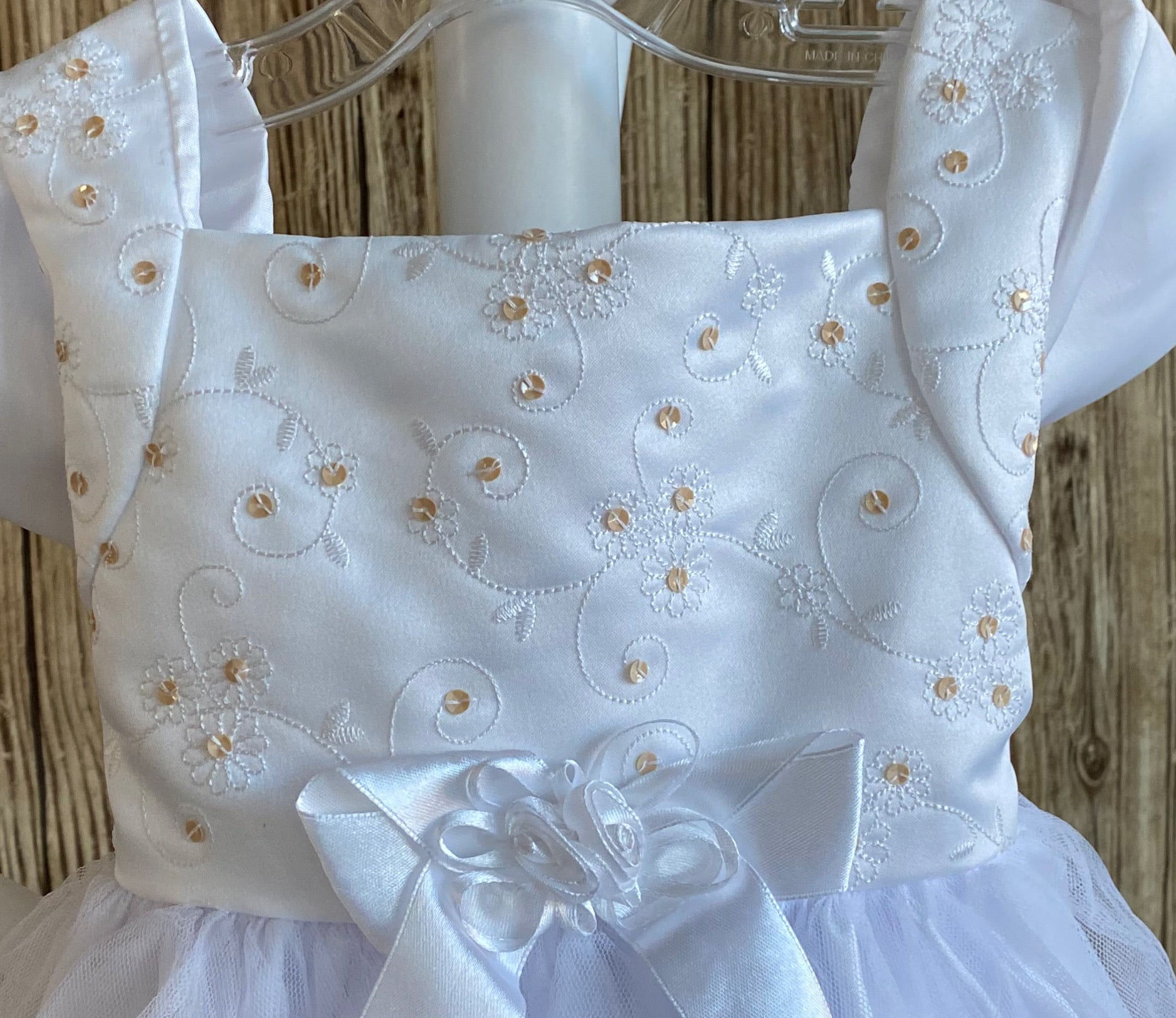  This a beautiful, one-of-a-kind baptism gown.  A lovely gown for a precious child.  White, size 12M Satin bodice with gold (sequins) and white embroidered flowers White cap sleeve  Large bow with floral center on bodice edge Tulle skirting with white roses Ribbon edge around tulle skirt Large ribbon bow in back 