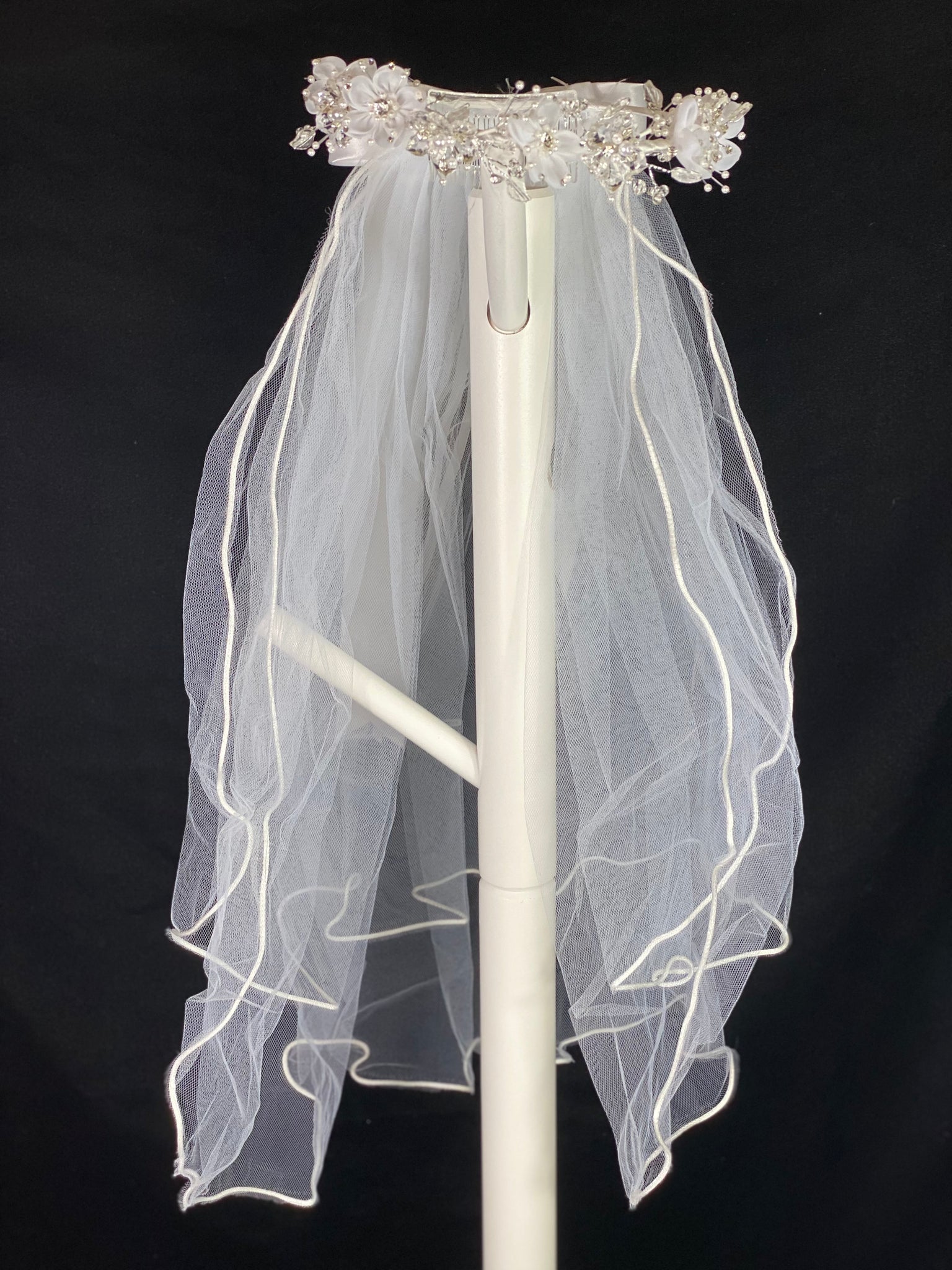 Elegant soft 2 layer tulle veil with delicate hand stitched braided satin trim around the edge and  handmade flower halo crown with veil with large white satin bow on back. Stain flowers with sparkling rhinestone petals and centers.  Crystal flowers between organza flowers. Beautiful crystal leaves sticking out around flowers.  This double layered veil reaches approximately 24" long, with a crown diameter of 6". Veil has 2" long, 3" wide, comb to secure it in place. 