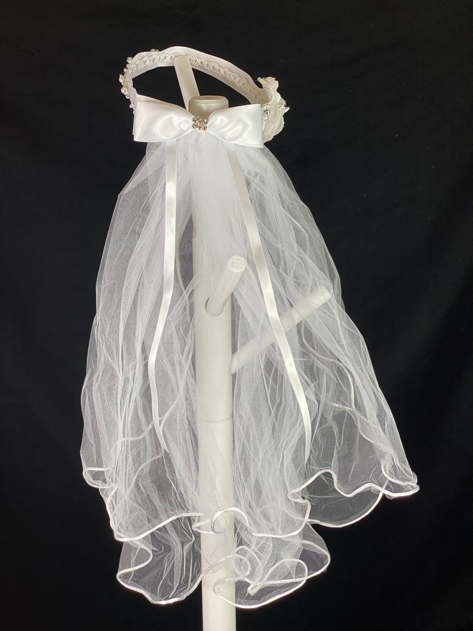 White Crown Veil with rhinestones.  Elegant soft 2 layer tulle veil with delicate hand stitched braided satin trim around the edge and handmade halo crown with with large white satin bow on back. Rhinestone vining on thick satin ribbon around crown. Large rose with rhinestone center on side of band.  This double layered veil reaches approximately 24" long, with a crown diameter of 6". Veil has 2" long, 3" wide, comb to secure it in place. 