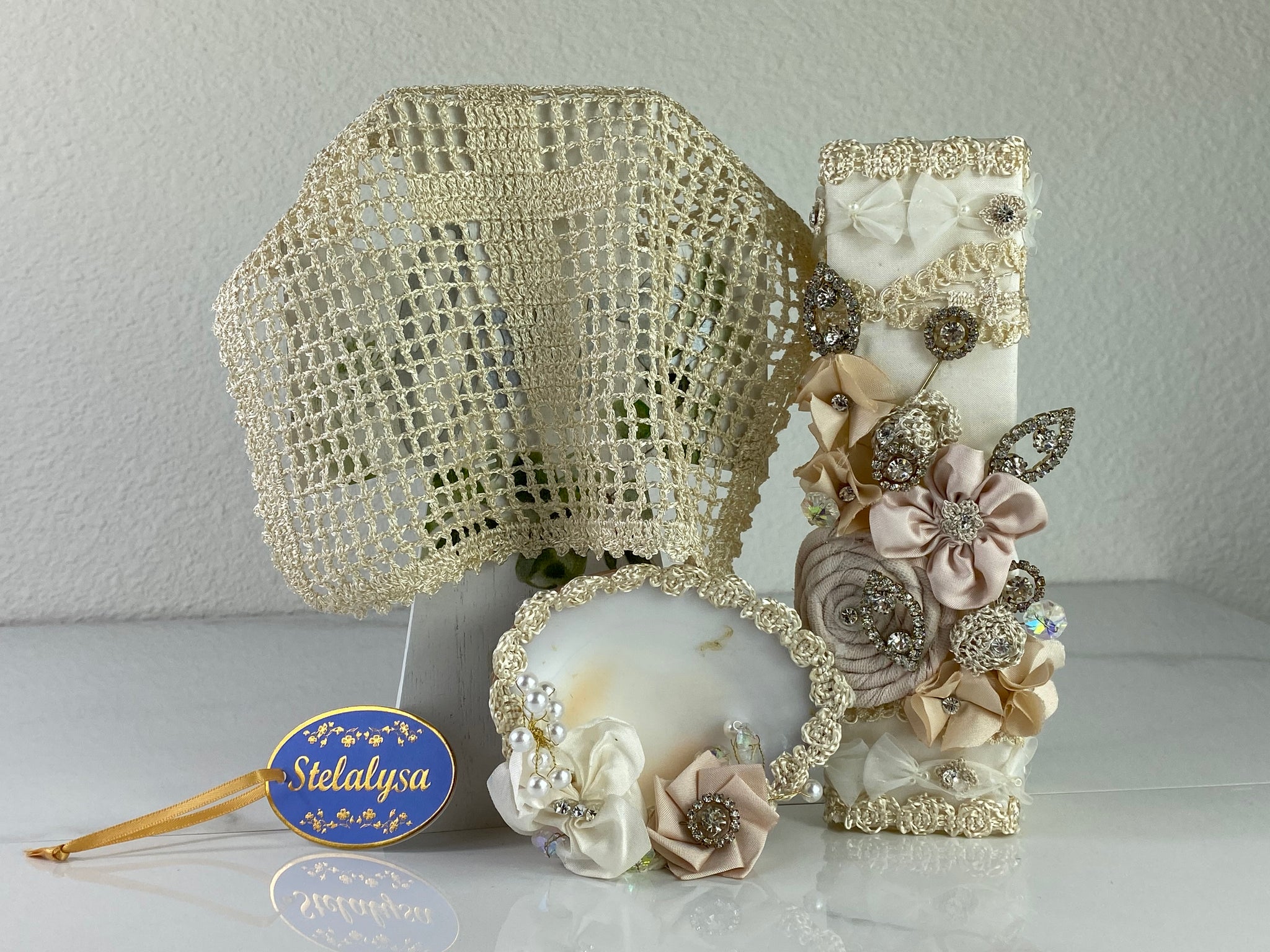 These one-of-a-kind Candle set is handmade and ivory in color.  This candle can also be use with a white baptism outfit because it has an array of light colors including white.   It is uniquely decorated with ribbon, pearls, crystals, flowers, and beads making it a gorgeous keepsake.   This candle is square in shape.    To match, the Shell is put together piece by piece to compliment the Candle and Handkerchief.  The Handkerchief is elegantly crotchet with a lovely cross