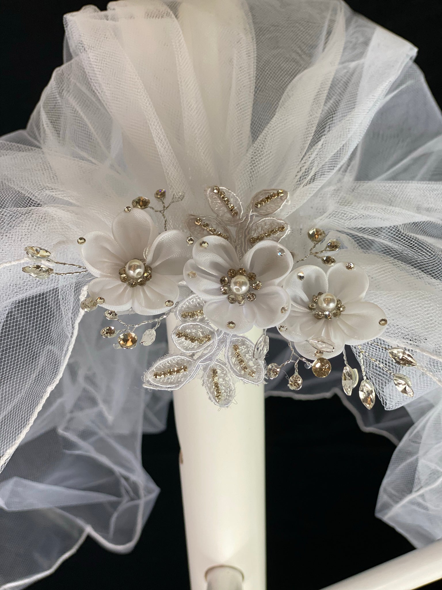 Veil - White Elegant First Communion Veil on Decorative Comb  Elegant soft 2 layer tulle veil with delicate hand stitched braided satin trim around the edge and handmade decorative comb with lace leaves. Beautiful organza flowers through center with pearl centers and rhinestones on petals. Embroidered leaves surrounding the flowers.   This double layered veil reaches approximately 21" long. Veil has 2" long, 3" wide, comb to secure it in place. 