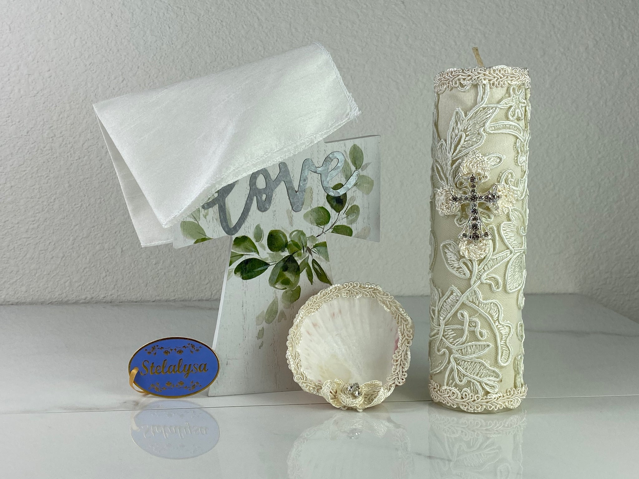 These one-of-a-kind Candle set is handmade and ivory in color.  This candle is beautifully wrapped in a unique lace design.   It is decorated with a cross made of rhinestones making it a gorgeous keepsake.   This candle is cylinder in shape.   To match, the Shell is put together piece by piece to compliment the Candle and Handkerchief.  The Handkerchief is made of satin and embroidered lace to match the Shell and Candle beautifully.  