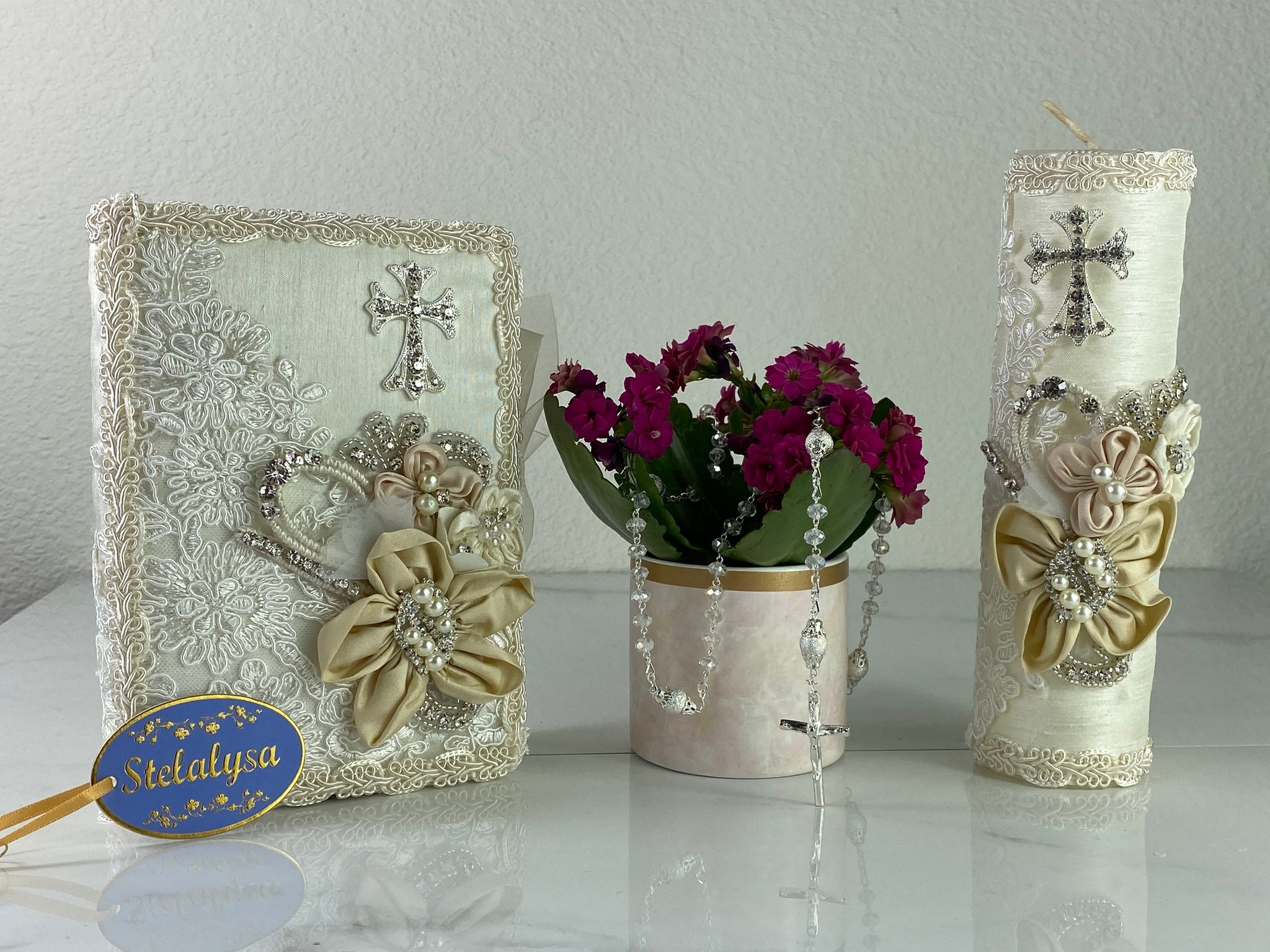 This ivory Bible Set - candle and bible is handmade and made using satin and lace.  It is elegantly designed with pearls, crystals, flowers in different pastel colors, and beads.  Each piece has a beautiful cross.  An elegant rosary complements this set.  The rosary is 16.5 in. long and Bible is 6.5 in. by 4.5 in. and the candles approximately the same height.  The Bible includes the Old and New Testament in English. 