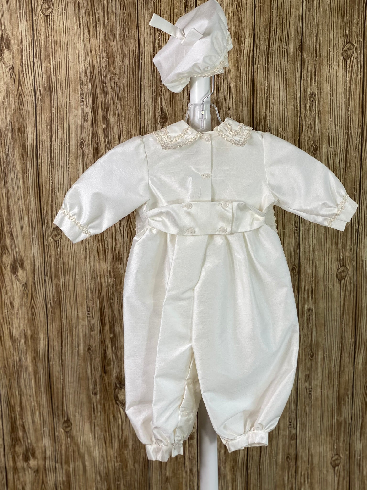 IVORY (pictures shown first)  3-piece ivory set including beret, one piece stole, romper Collared shirt with long sleeves Buttoning on pant cuffs Button closure on back of romper Wide embroidered trim along edge of stole and collar Thin embroidered trim along sleeve cuff edge Large pearl beaded cross on front of stole