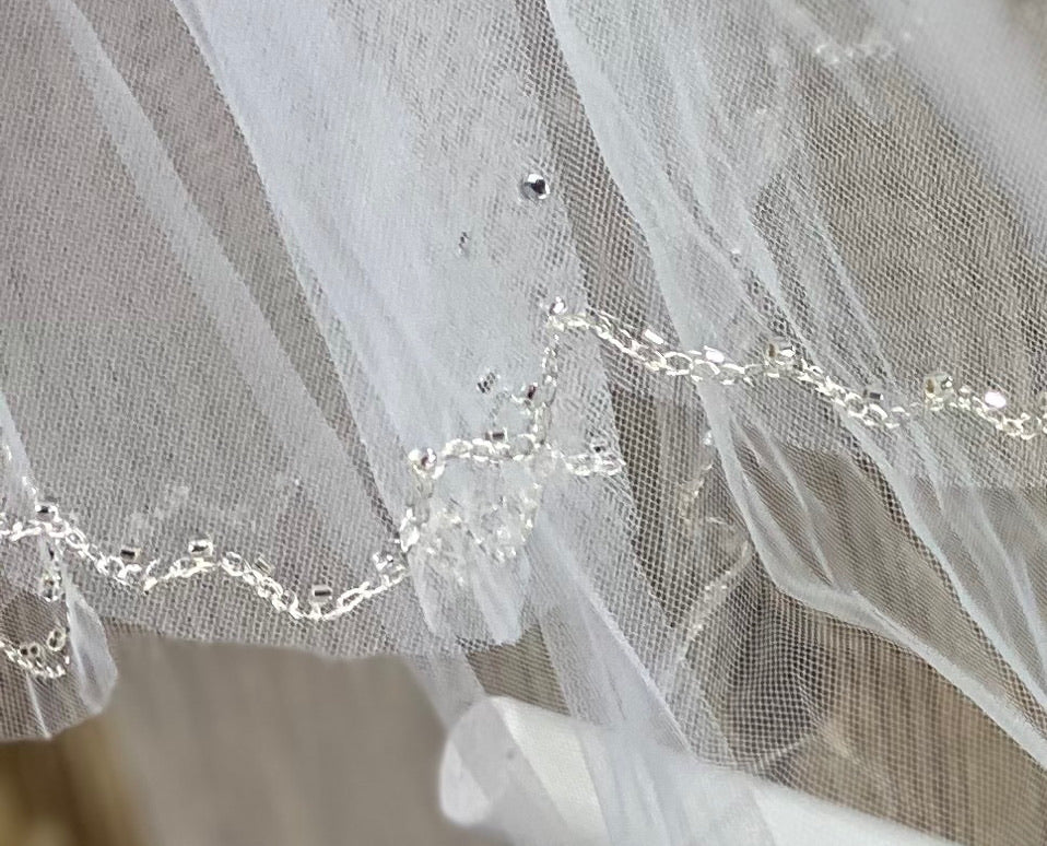 White - Scallop Jewel Veil for First Communion   Elegant soft 2 layer tulle veil with delicate hand stitched beads and scattered sequins.  Veil length - 29 in. long, comb - 11.5 cm wide  Materials:  sturdy plastic comb, soft tulle, and appliques - beads and sequins.