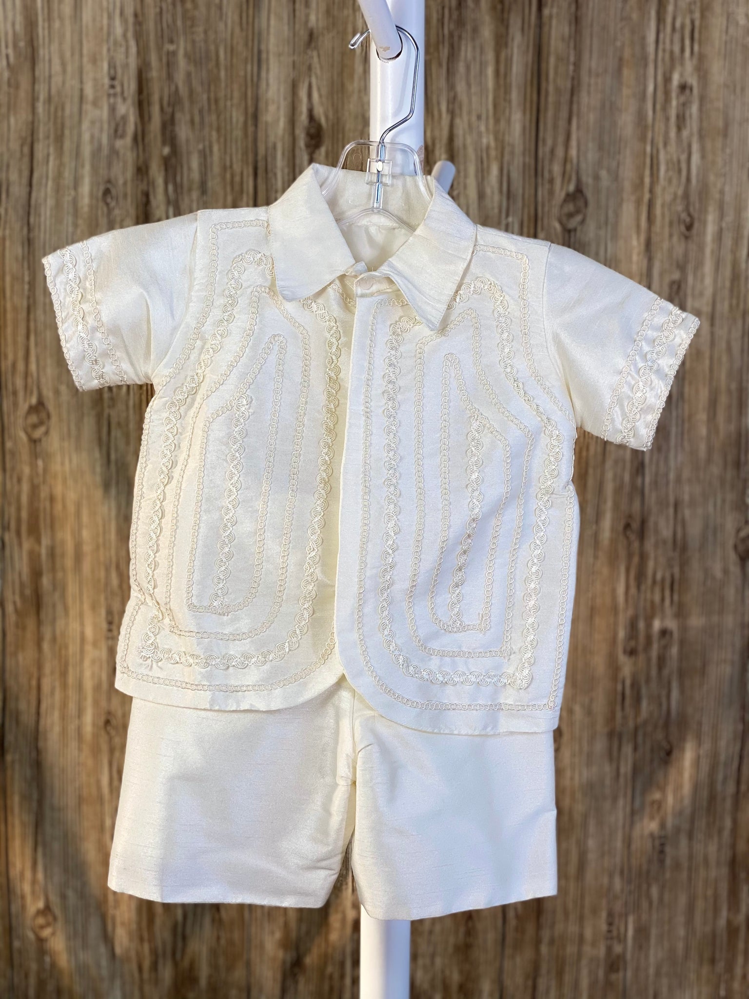 This a beautiful, one-of-a-kind boy’s baptism gown/set.  Lovely clothes for a precious child.  Ivory, size 24M 2- piece set including shirt and suspender pants Collared shirt with short sleeves Simple satin pants Twisted layered trim along shirt cuffs Twisted layered trim on shirt bodice Hidden button closure in front Elastic on the back of pants